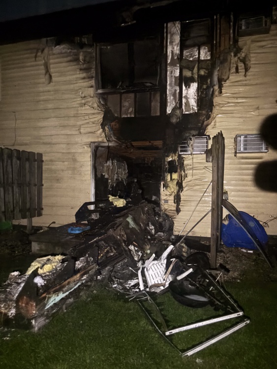 Burned items spill out of doorway of fire-damaged home