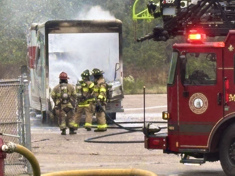 Firefighters spray attack a fire inside a storage trailer