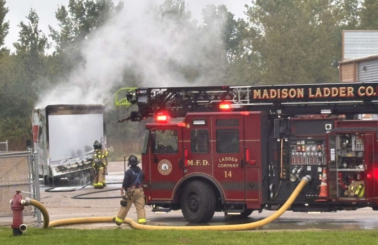 Firefighter sprays down hot spots in back of cargo trailer