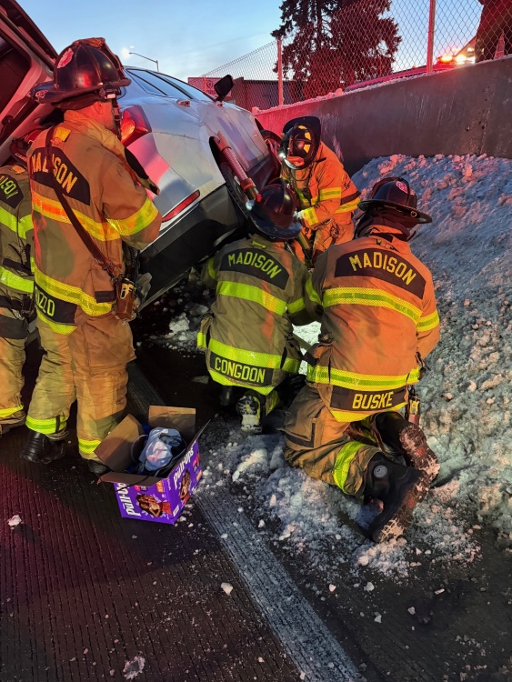 Ladder Company 2 stabilizes lopsided vehicle resting against highway barrier