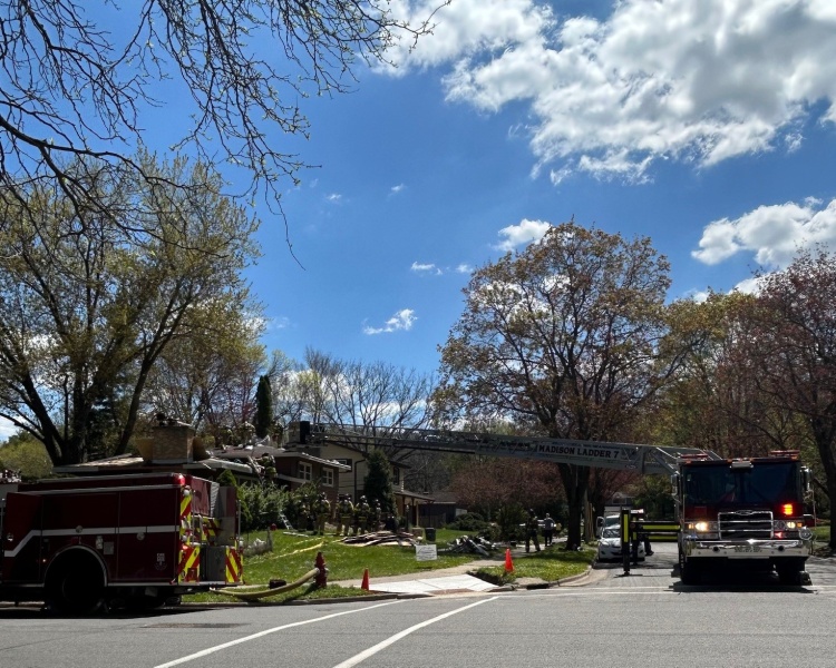 Fire trucks surround home with aerial ladder extended to roof