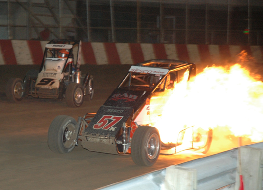 Racecar engulfed in flames on a racetrack