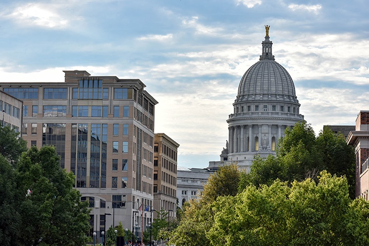 WI State Capitol surrounded by buildings and trees.