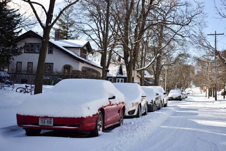 Cars parked on one side of a snowy street