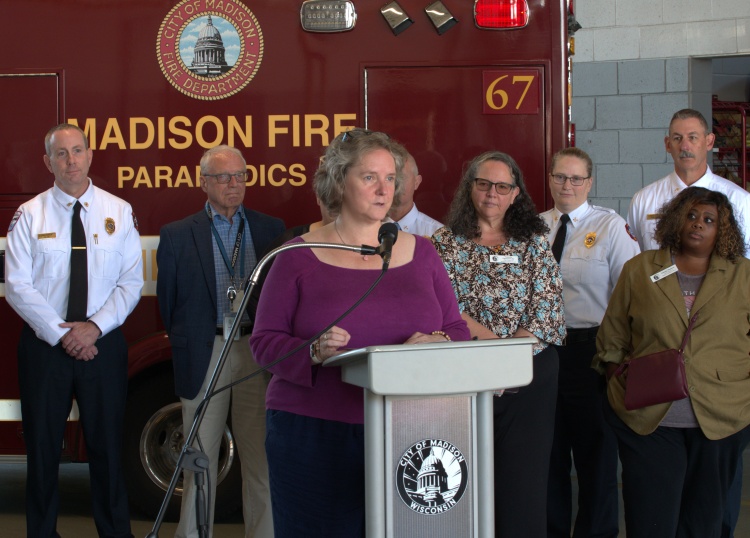 The Mayor delivering her budget message in front of Alders, Firefighters, and an ambulance