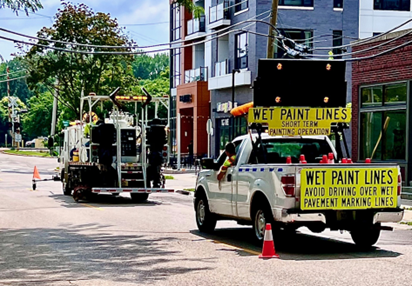 two trucks in a work zone painting lane lines on the road.  