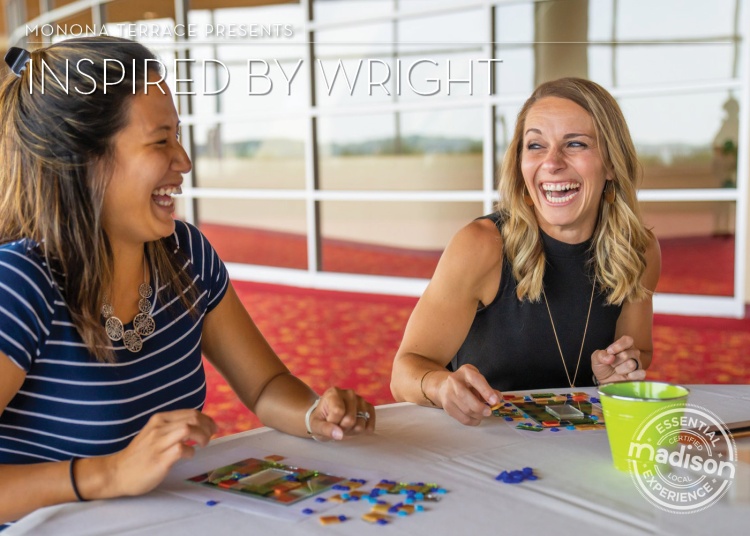 2 younger women, smiling & laughing, seated at a table creating glass art 