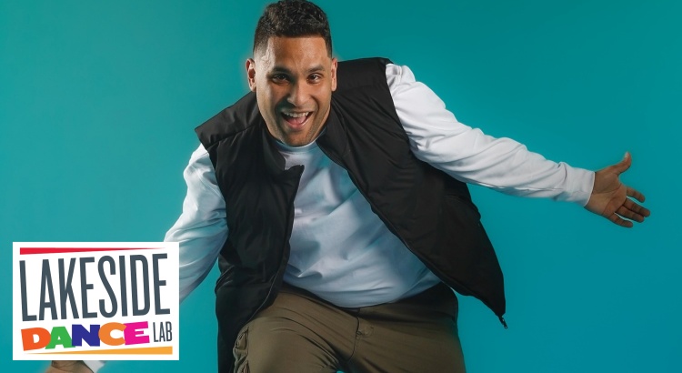 Smiling guy in a dance pose against neutral blue background