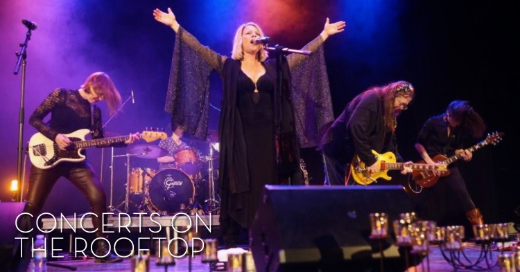 Members of the band gold dust women on stage with arms raised in song
