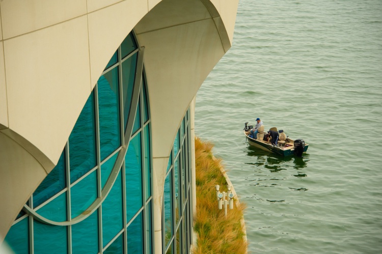 The side of Monona Terrace with a fishing boat on Lake Monona in the background 
