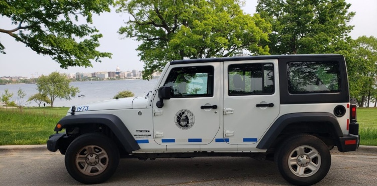 Side view of a Parking Enforcement vehicle, white truck with black roof and the City of Madison Logo on the door