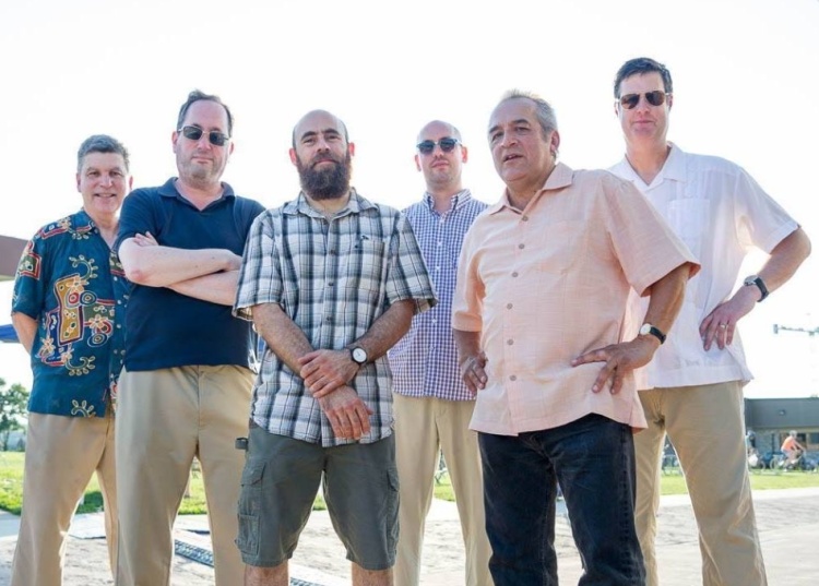 Six men stand outside in a line