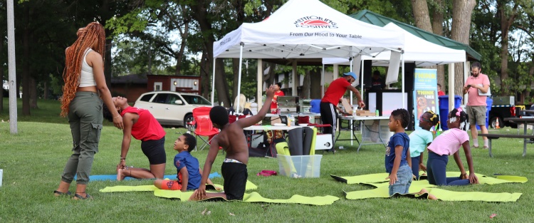 kids doing yoga, adult instructor, on grass in a park