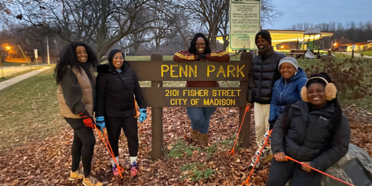 adults standing by Penn Park sign