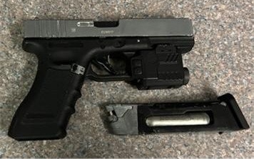 Realistic looking black facsimile firearm is placed on a table.