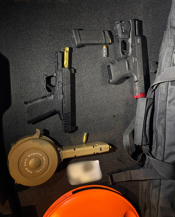 Two black handguns are displayed on a table during a weapons violation investigation.