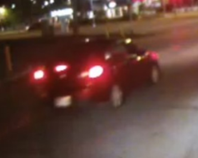 Traffic camera photo showing a red sedan involved in a hit-and-run crash.