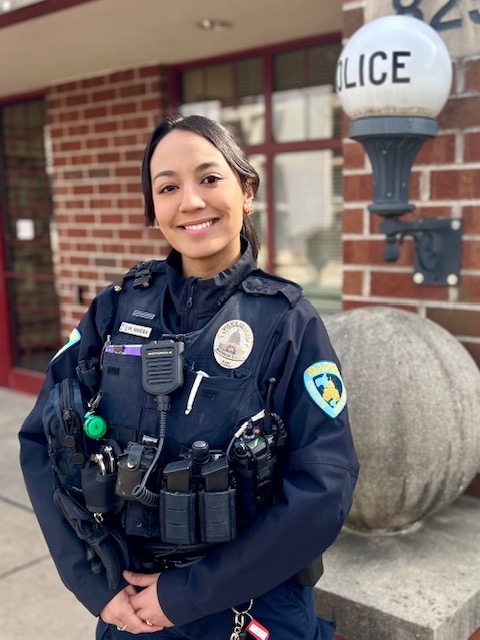 Female police officer Milcah Rivera stands in front of the South District Police Station.