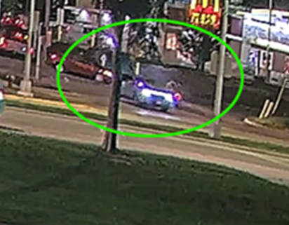 Traffic camera photo showing a red sedan involved in a hit-and-run crash.