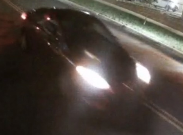 Traffic camera photo showing a red sedan involved in a hit-and-run crash.
