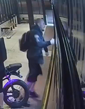 Man wearing shorts and a sweatshirt stands at a bus station before hitting and damaging a bus.