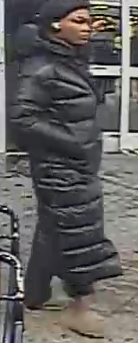 Woman wearing a long black winter coat believed to be a suspect in a theft case