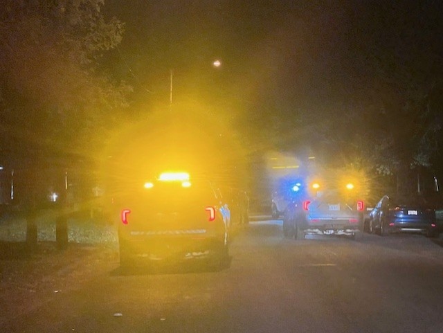 Police squad car line the road as officers investigate a fatal shooting.