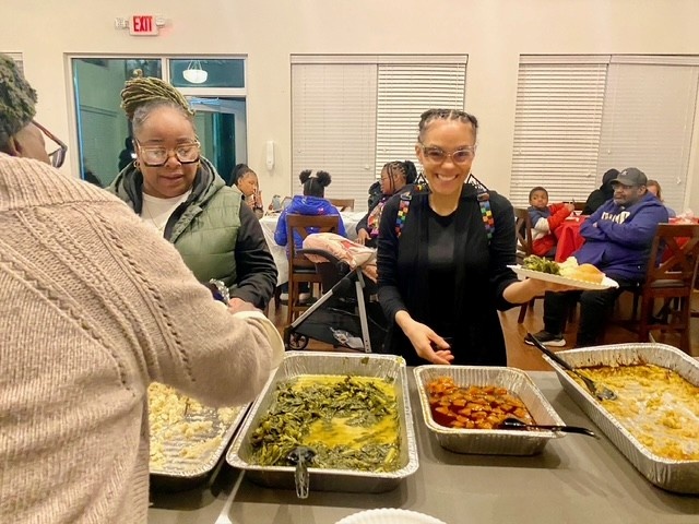 East District Community Advisory Board members serve dinner to community members.