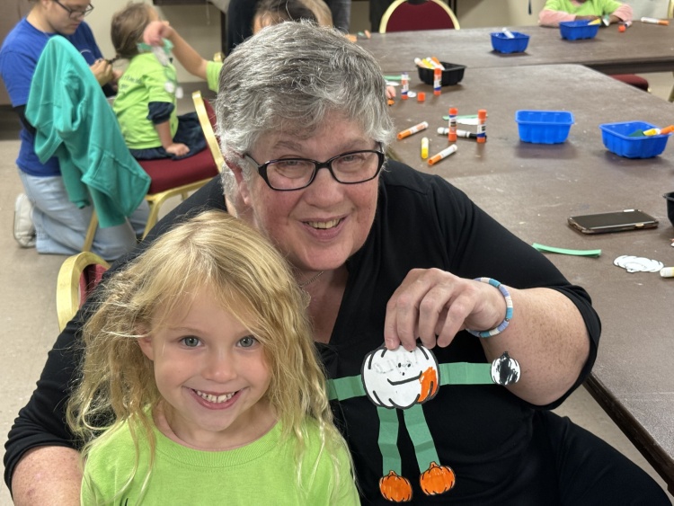 An older woman and a preschool child holding a project that they did together.