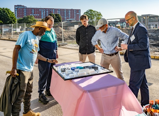 People gathered around a table looking at a 3D printed model of the Triangle redevelopment