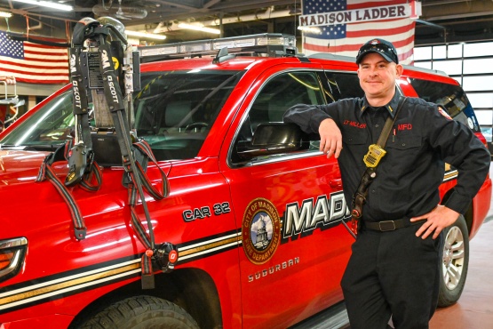 Lieutenant Mark Miller leans against a vehicle with a firefighter airpack on display