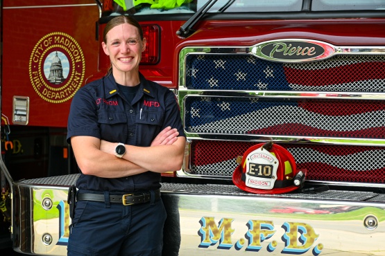 Laura Prom stands in front of a fire engine with her helmet on display