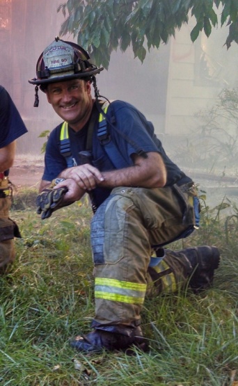 Paul Ripp kneeling in front of a training house burn