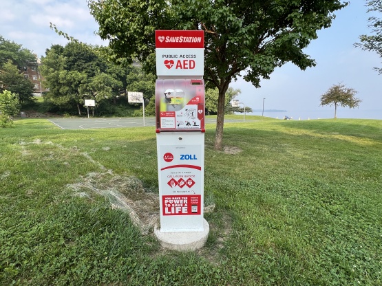 AED SaveStation situated in the grass with a basketball court behind it