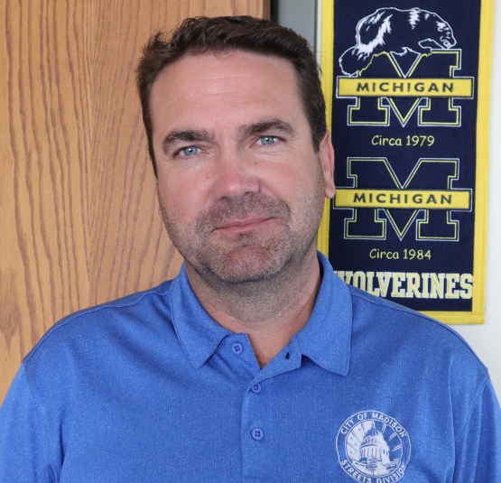 A close-up of Charlie Romines with a Michigan University banner in the background