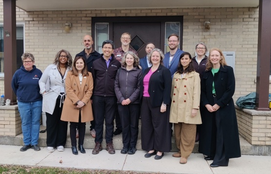 Officials poising in front of a cream brick building
