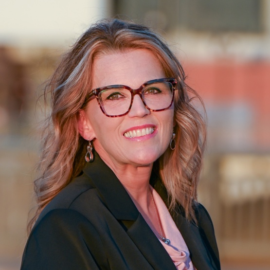 A profile shot of Christine Knapp, who is wearing a black jacket, a light-colored shirt and has tortoise shell glasses