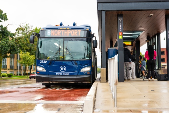 Metro electric bus docked at a BRT station on a rainy day.