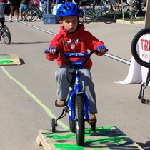 child with blue helmet learning to ride a bicycle with training wheels