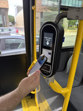 A passenger using a virtual wallet device on the bus fare reader.