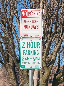 Clean Streets Clean Lakes posted restriction - No Parking Monday (in red text), above 2 hour posted restriction (in green text)