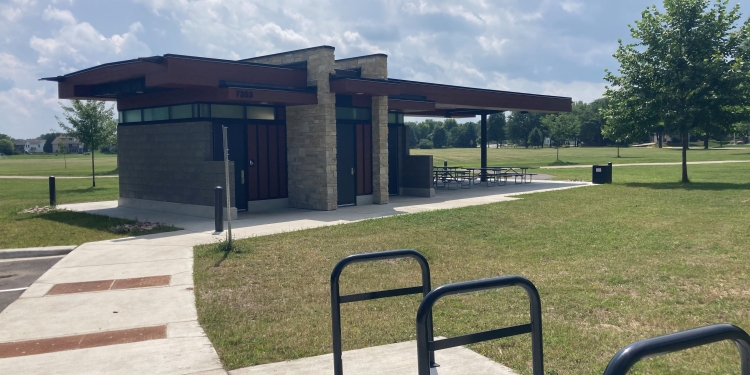 bike racks next to a paved path leading to the park shelter