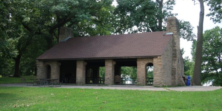Green grass and park shelter with trees in background.