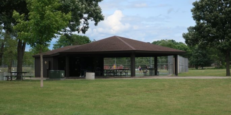 Park shelter with grassy area and trees.