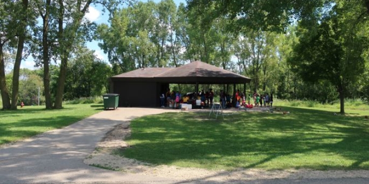 Path leads up to a shelter where people are gathered. The shelter is surrounded by trees.