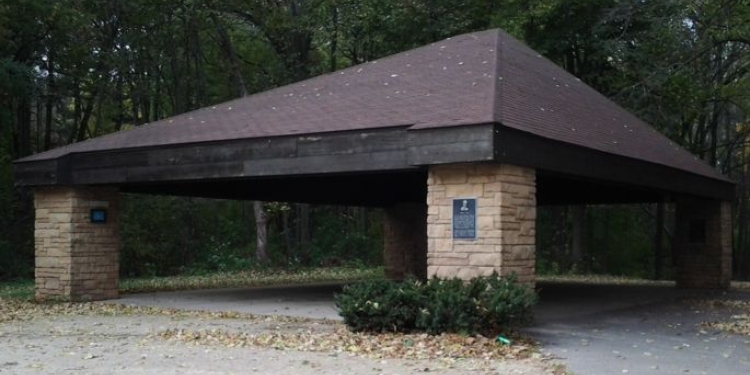 Paved path leads to a shelter. There are trees in the background.