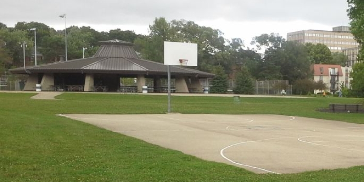 Basketball court with a shelter and other buildings in the background.