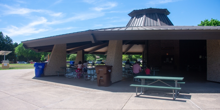 Basketball court with a shelter and other buildings in the background.