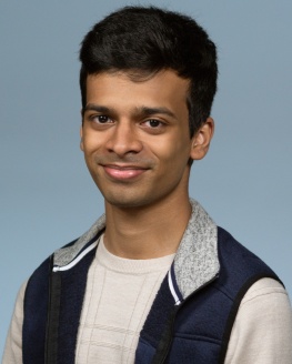 MGR is wearing a tan t-shirt with a black jacket and tan sleeves.