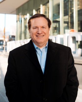 Alder Verveer is standing in front of Central library which is located in his district. He is smiling and wearing a black coat.